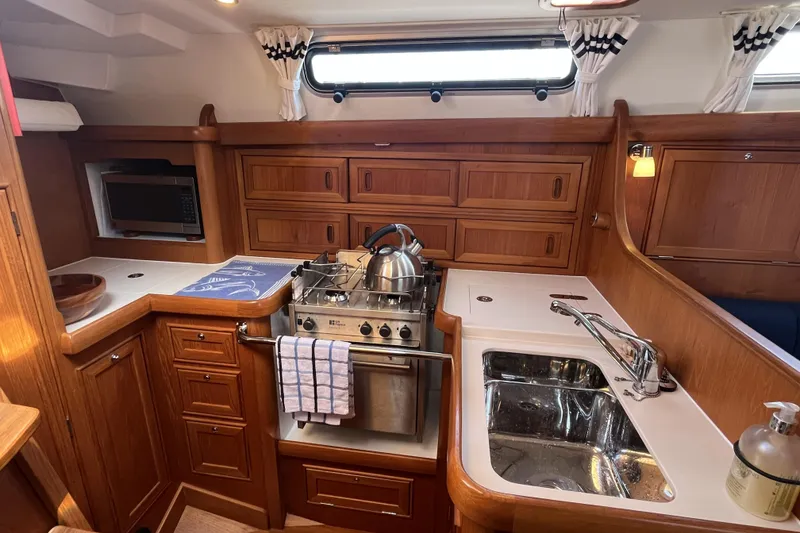 Slide: The Image of 2017 Rustler 37 yacht kitchen with wooden cabinetry, stove, sink, and microwave. - 29