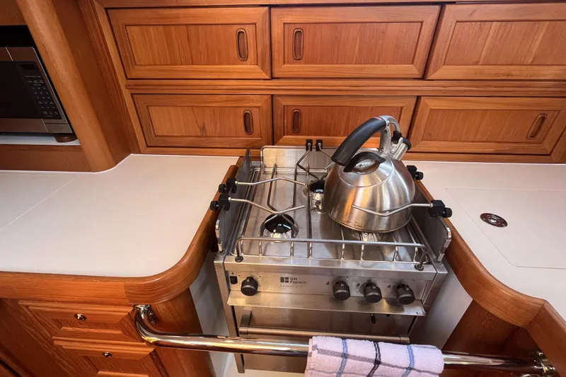 Slide: The Image of Wooden yacht kitchen with stove, kettle, and cabinetry in a 2017 Rustler 37. - 31