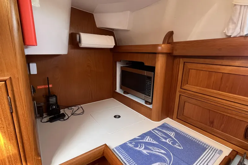 Slide: The Image of 2017 Rustler 37 yacht interior with microwave, wooden cabinetry, and nautical-themed towel. - 32