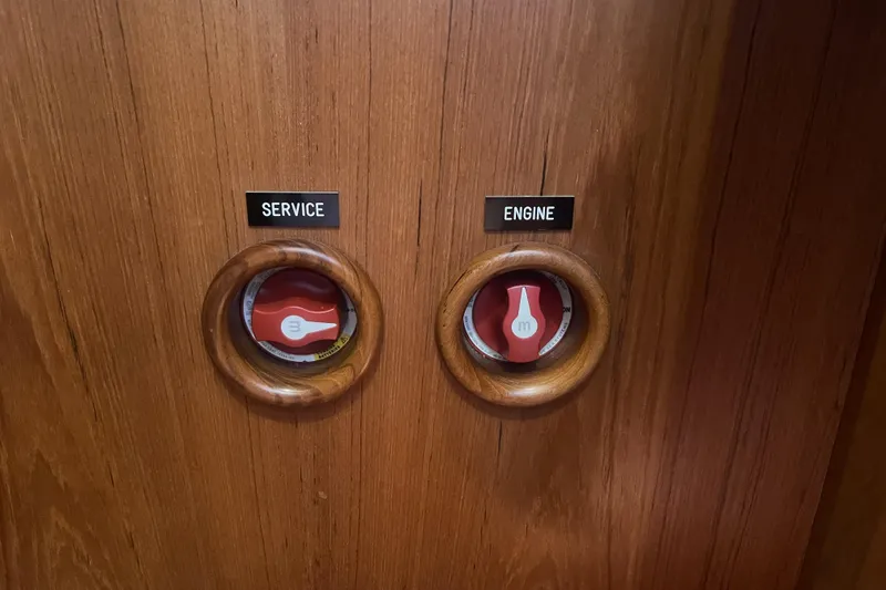Slide: The Image of Wooden panel with labeled service and engine switches on a 2017 Rustler 37 yacht. - 52