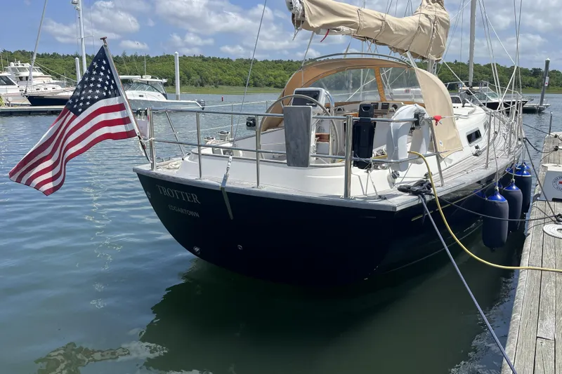 Slide: The Image of 2017 Rustler 37 sailboat docked with American flag, clear sky, and calm water. - 74