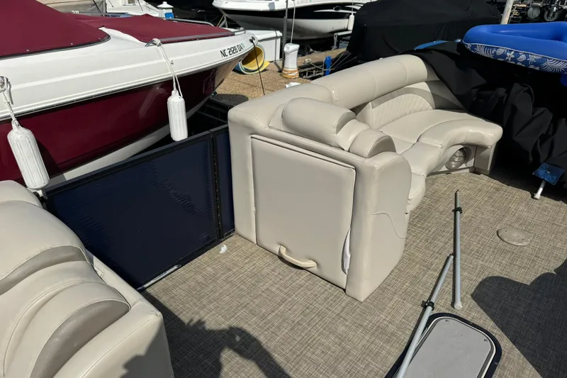 Slide: The Image of 2017 Harris FloteBote 240 Sunliner interior with beige seating and boat docked nearby. - 9