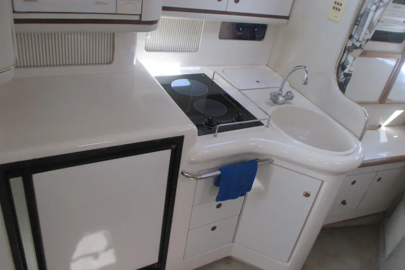 Slide: The Image of 1997 Sea Ray Sundancer 330 yacht kitchen with stove, sink, and storage cabinets. - 15