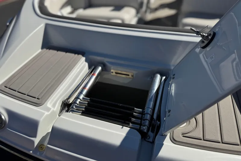 Slide: The Image of 2020 Crownline Eclipse E255 SURF boat ladder compartment, open with visible steps. - 11
