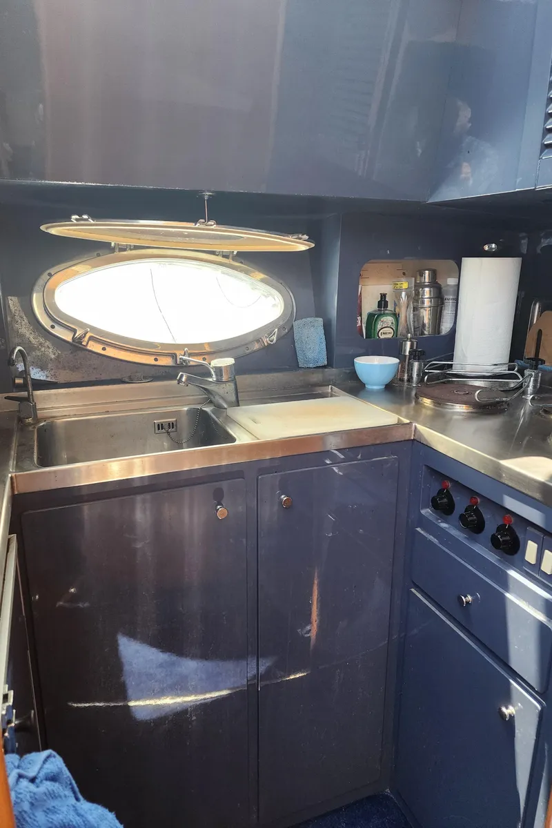 Slide: The Image of 1987 Riva SuperAmerica yacht kitchen with stainless steel sink and porthole window. - 16