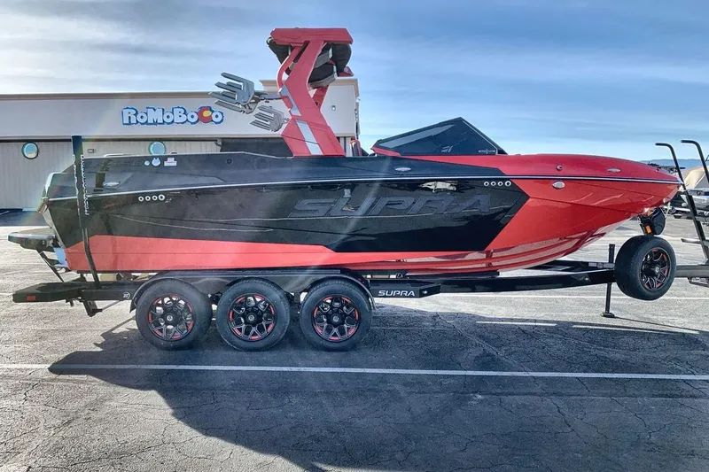 Slide: The Image of 2026 Supra SL 550 boat in red and black on a trailer in parking lot. - 6
