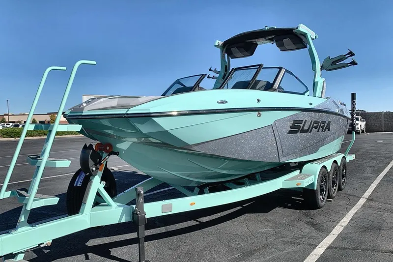The Image of 2026 Supra SL 550 boat on trailer, sleek design, mint green color, parked outdoors. - 1