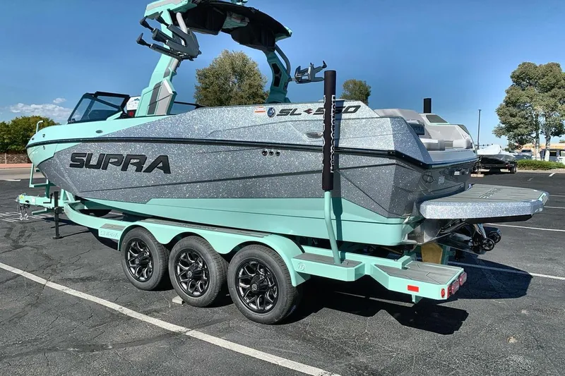 Slide: The Image of 2026 Supra SL 550 boat on trailer, mint green and silver design, parked outdoors. - 3