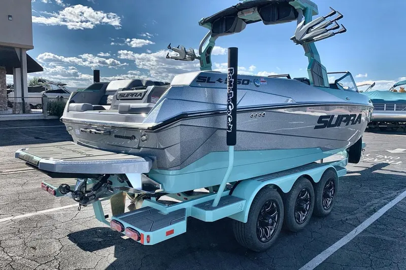 Slide: The Image of 2026 Supra SL 550 boat on a trailer, parked outdoors under a clear sky. - 5