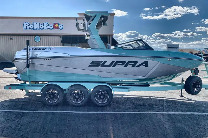 Slide: The Image of 2026 Supra SL 550 boat on trailer in parking lot, clear sky background. - 6