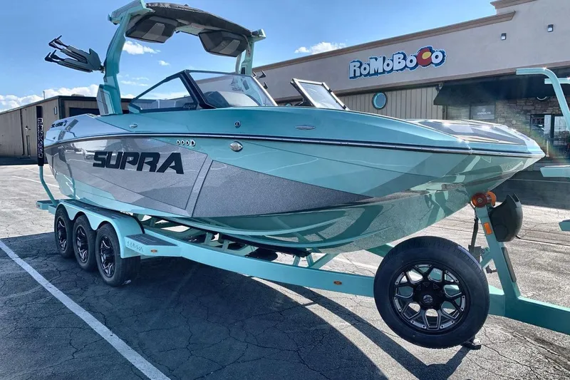 Slide: The Image of 2026 Supra SL 550 boat on trailer, parked outside a building under a clear sky. - 7