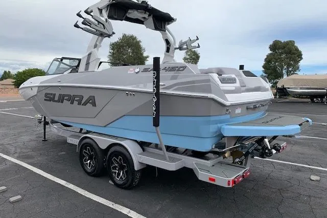 Slide: The Image of 2026 Supra SA 450 boat on trailer, gray and blue design, parked outdoors. - 3