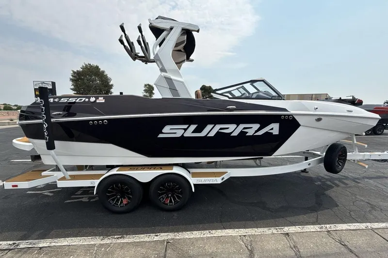 Slide: The Image of 2025 Supra SA 550 boat on trailer, sleek black and white design, parked outdoors. - 6