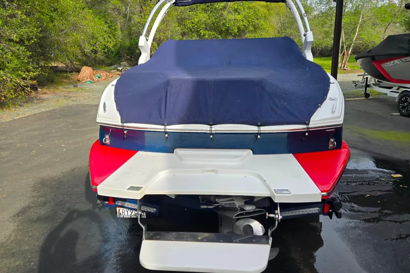 Slide: The Image of Rear view of a 2018 Cobalt CS23 boat with a blue cover, parked outdoors. - 17
