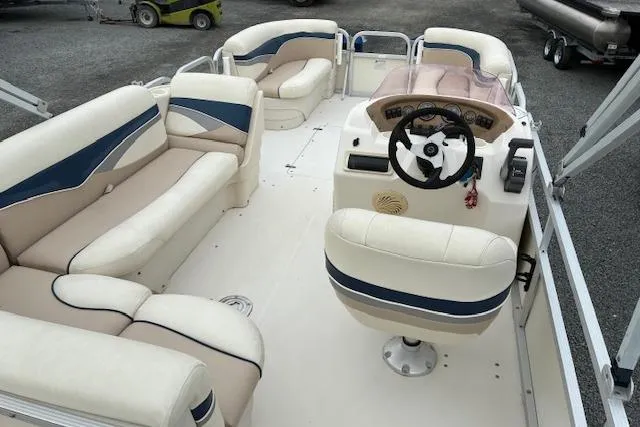 Slide: The Image of 2007 SouthWind 229 Deck Boat interior with beige and blue seating, steering console, and spacious layout. - 2