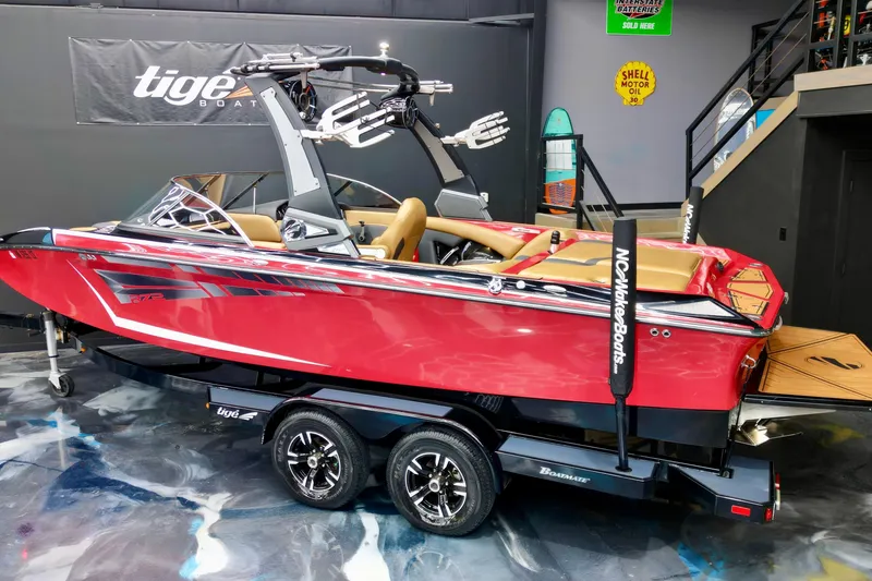 Slide: The Image of 2017 Tigé RZX2 boat in showroom, red exterior, tan interior, on trailer. - 4