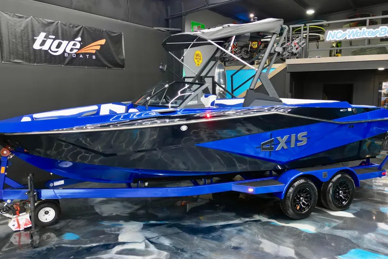 Slide: The Image of 2025 Axis T220 boat in showroom, vibrant blue and black design, on trailer. - 13