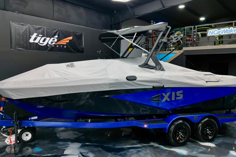 Slide: The Image of 2025 Axis T220 boat with cover on blue trailer in showroom. - 14