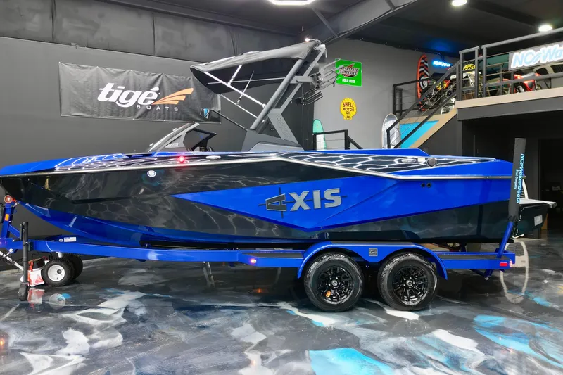 Slide: The Image of 2025 Axis T220 boat in showroom, vibrant blue and black design on trailer. - 3