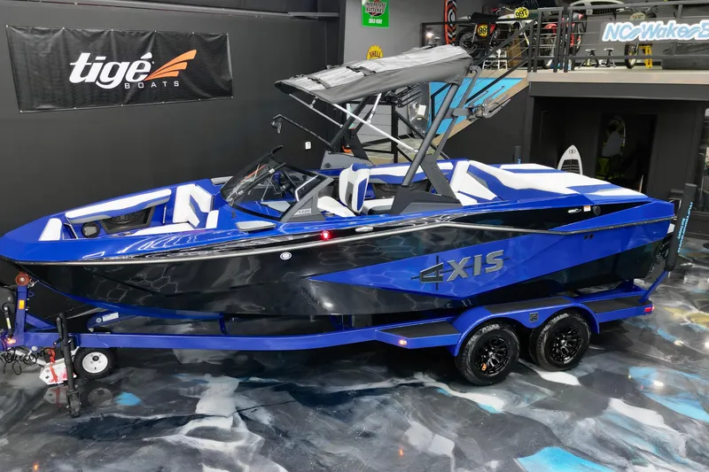 Slide: The Image of 2025 Axis T220 boat in showroom, blue and black design, on trailer. - 4