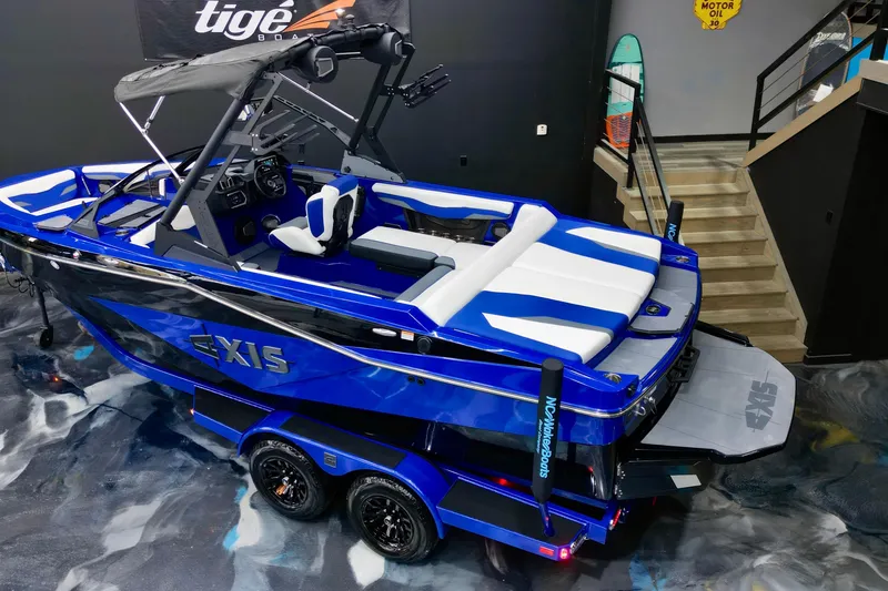 Slide: The Image of 2025 Axis T220 boat in showroom, blue and white design, sleek and modern appearance. - 5