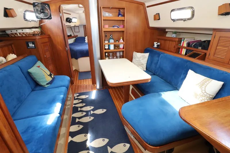 Slide: The Image of Interior of 1996 Island Packet 40 sailboat with blue seating and wooden accents. - 23