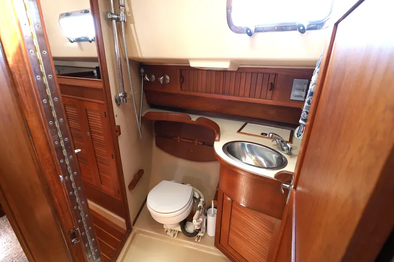Slide: The Image of 1996 Island Packet 40 yacht bathroom with wooden cabinetry and stainless steel sink. - 28