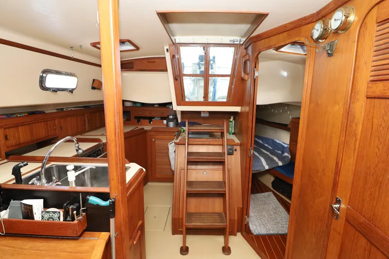 Slide: The Image of Interior of a 1996 Island Packet 40 sailboat, featuring wood finishes and a compact kitchen. - 30