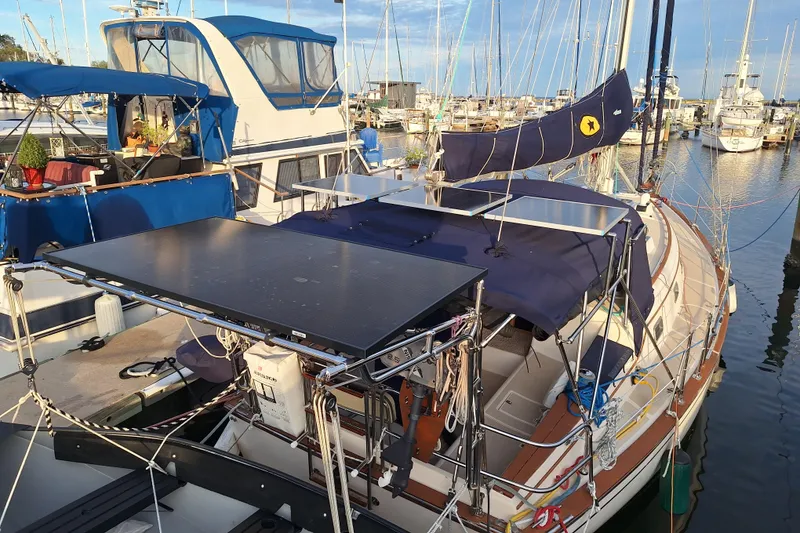 Slide: The Image of 1996 Island Packet 40 sailboat docked with solar panels and blue canopy in a marina. - 46