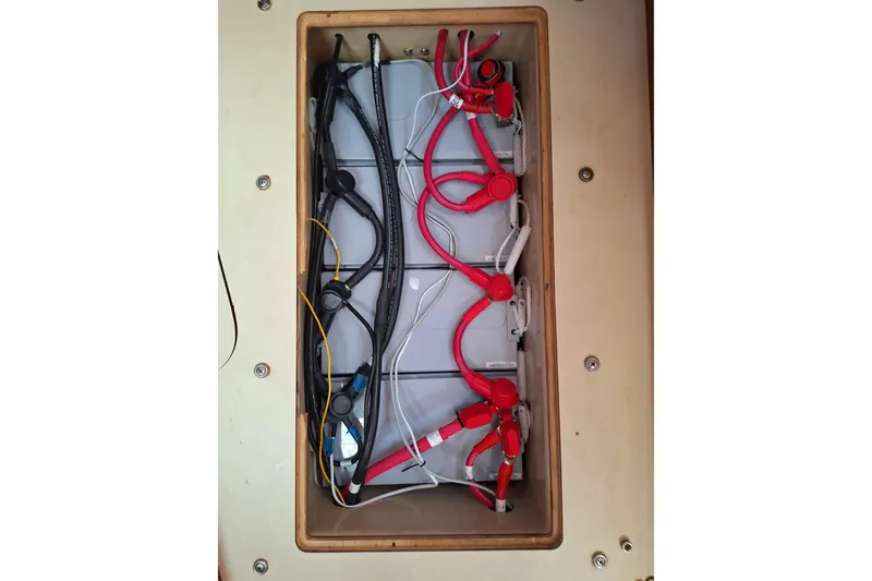 Slide: The Image of Battery compartment of a 1996 Island Packet 40 sailboat with red and black cables. - 56