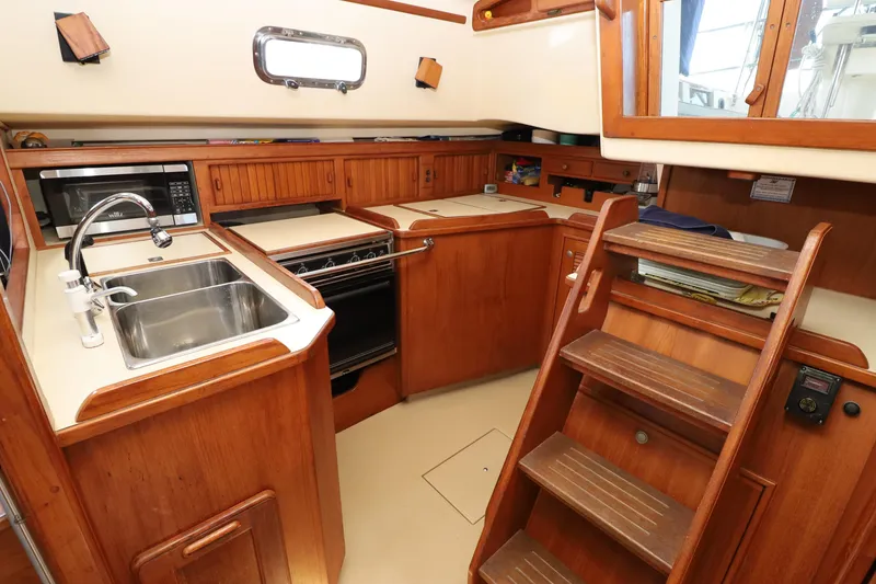 Slide: The Image of 1996 Island Packet 40 yacht kitchen with wooden cabinetry, sink, stove, and microwave. - 8