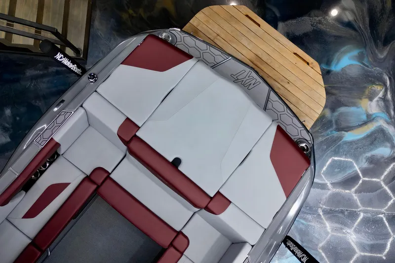 Slide: The Image of 2023 MasterCraft NXT24 boat interior with red and gray seating, wooden deck. - 10