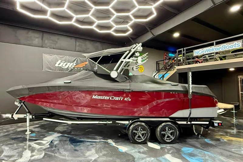 Slide: The Image of 2023 MasterCraft NXT24 boat in showroom, covered and on trailer. - 16