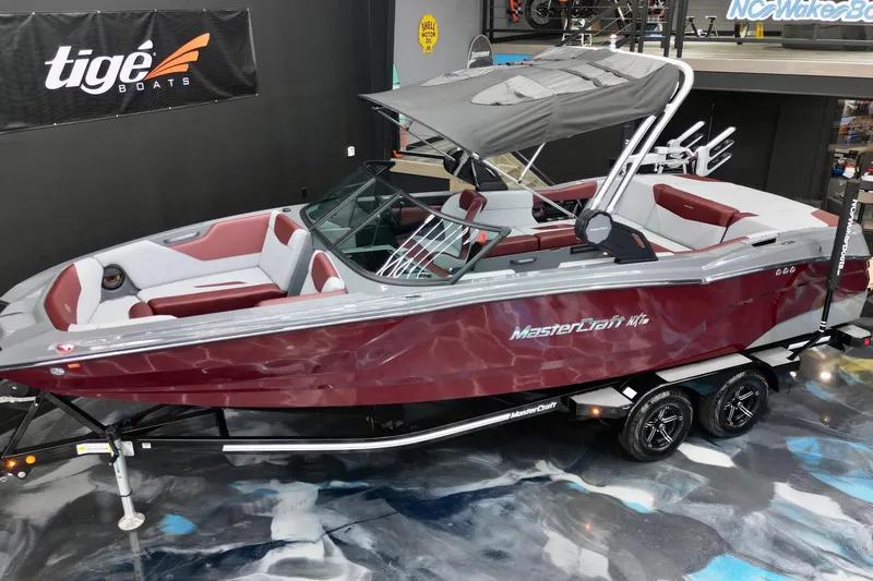 Slide: The Image of 2023 MasterCraft NXT24 boat with maroon and white interior, displayed indoors on a trailer. - 17