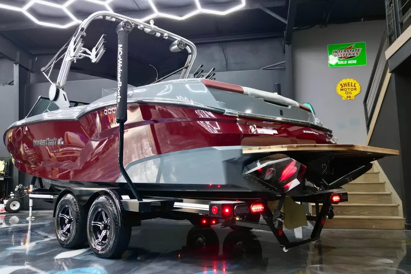 Slide: The Image of 2023 MasterCraft NXT24 boat in showroom, featuring sleek design and vibrant red color. - 2