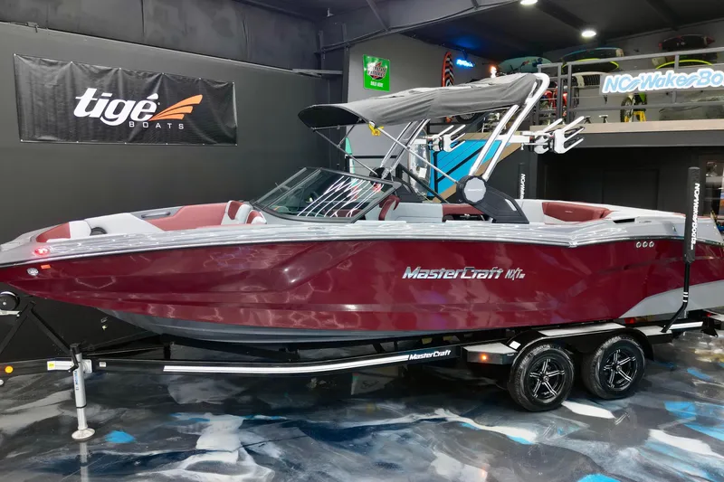 Slide: The Image of 2023 MasterCraft NXT24 boat in showroom, maroon color, on trailer. - 4