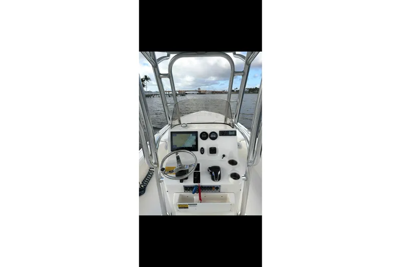 Slide: The Image of 2023 Key West 250 Bay Reef boat dashboard with steering wheel and navigation equipment. - 6
