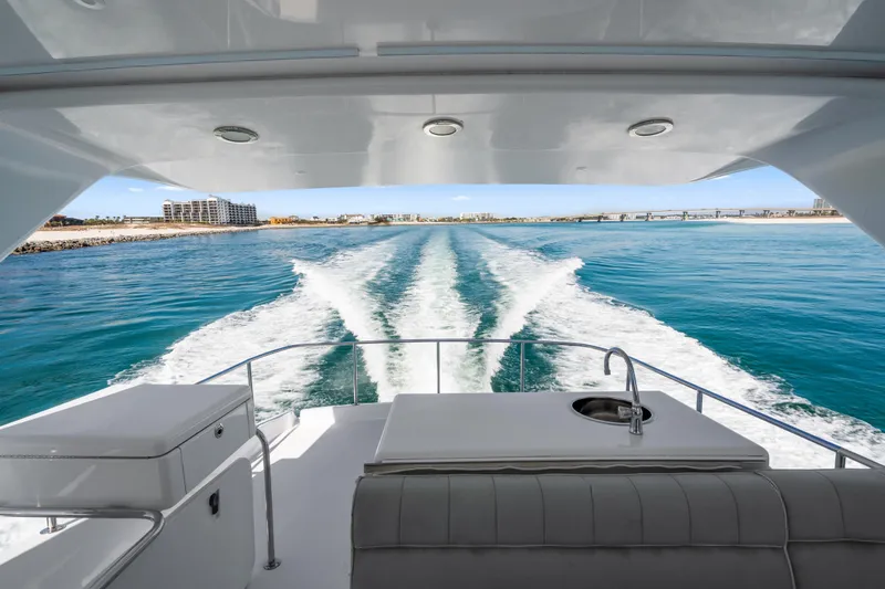 Slide: The Image of Aft view from 2013 Hatteras 60 Motor Yacht cruising on clear blue waters. - 64