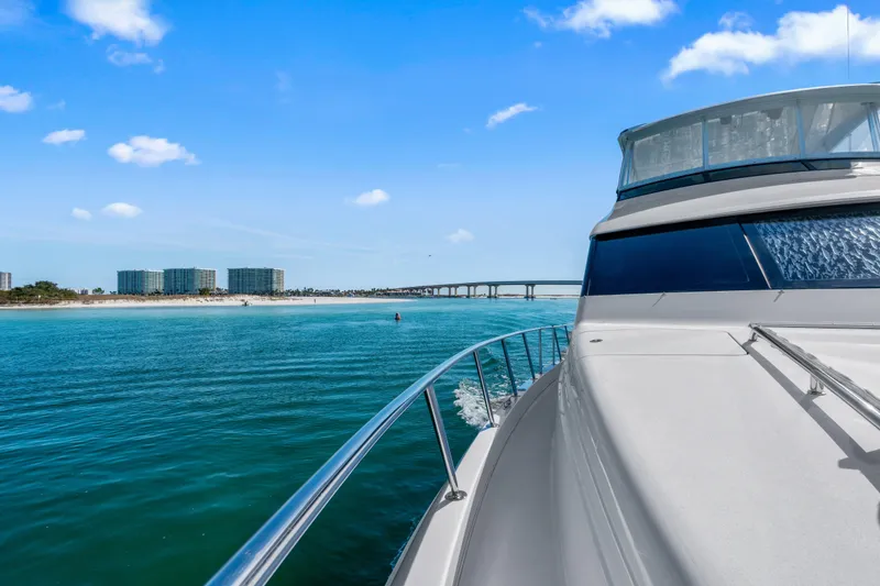 Slide: The Image of 2013 Hatteras 60 Motor Yacht cruising near a scenic coastal bridge and beachfront. - 68
