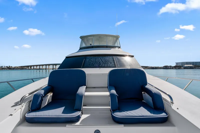 Slide: The Image of 2013 Hatteras 60 Motor Yacht with blue chairs on deck, under clear sky. - 69