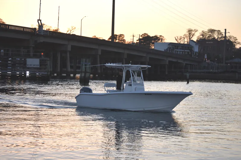 The Image of 2007 Tidewater 216 CC Adventure boat cruising near a bridge at sunset. - 0