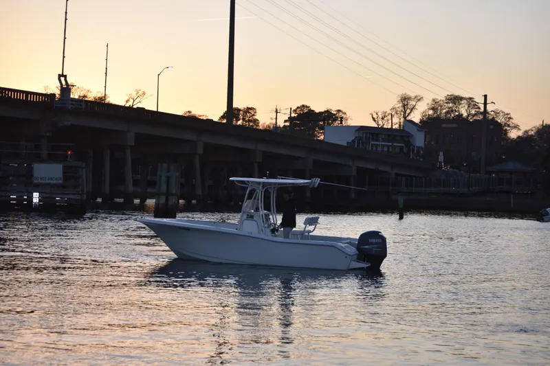 Slide: The Image of 2007 Tidewater 216 CC Adventure boat on water at sunset near a bridge. - 3