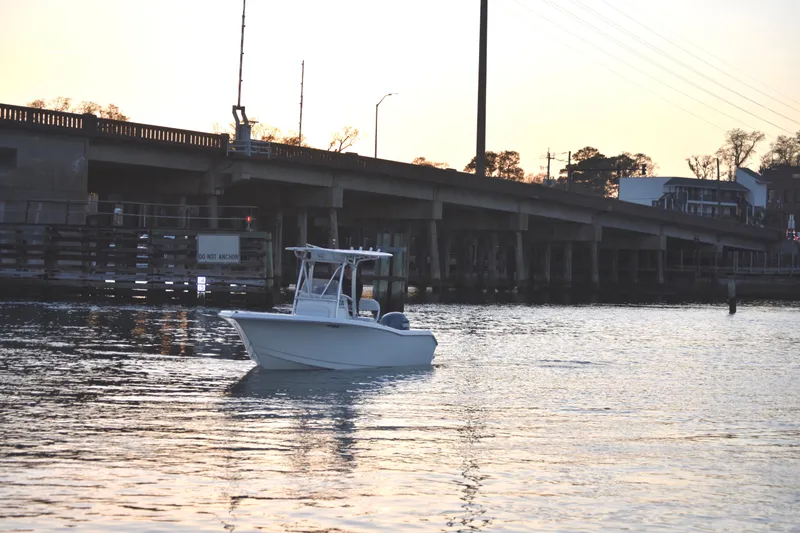 Slide: The Image of 2007 Tidewater 216 CC Adventure boat on calm water near a bridge at sunset. - 4