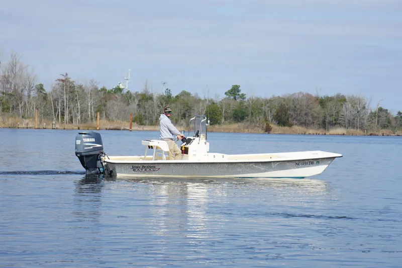 Slide: The Image of 2005 Jones Brothers Bateau 20 boat cruising on a calm lake with trees in the background. - 2