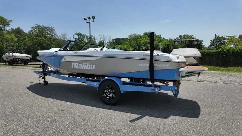 Slide: The Image of 2025 Malibu TXi boat parked on trailer outdoors. - 3