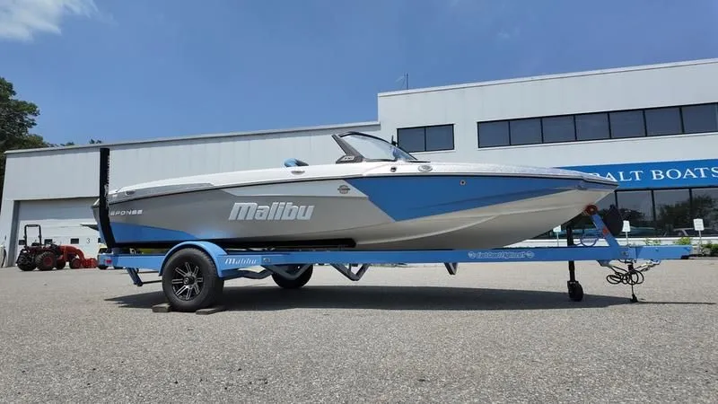 Slide: The Image of 2025 Malibu TXi boat on trailer in front of building. - 5