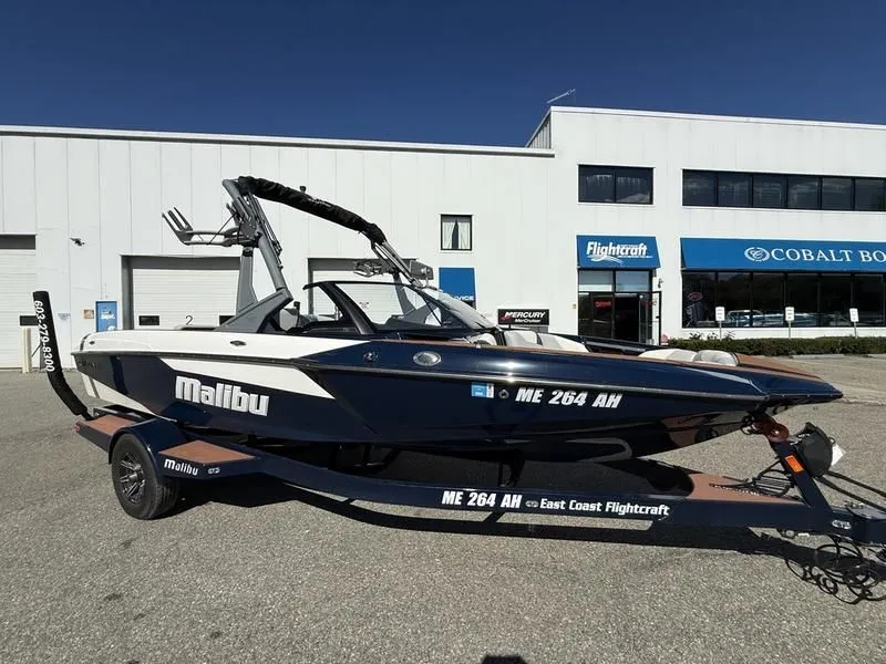 The Image of 2024 Malibu TXi boat parked in front of a building. - 1