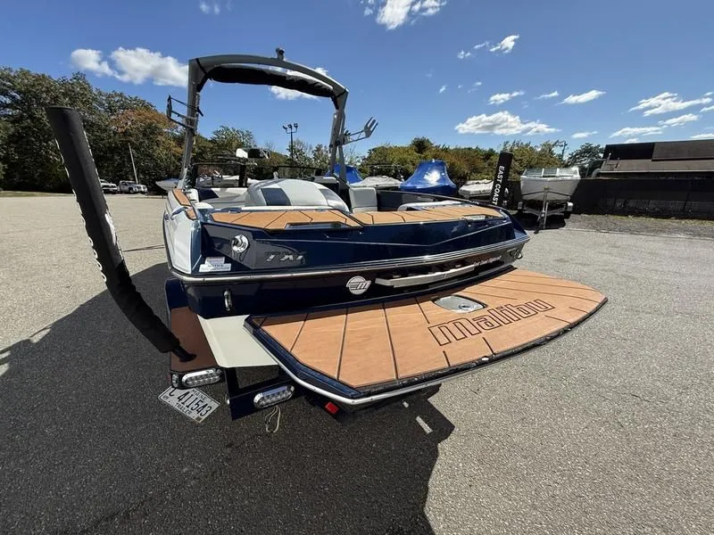 Slide: The Image of 2024 Malibu TXi boat parked outdoors on a sunny day. - 10
