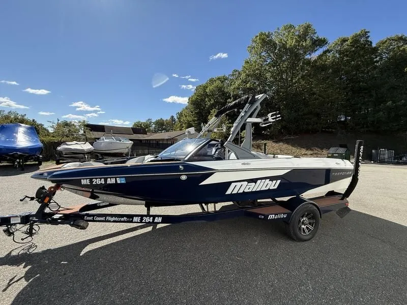 Slide: The Image of 2024 Malibu TXi boat parked on trailer outdoors. - 17