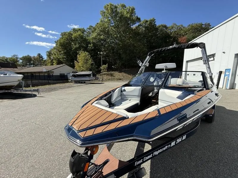 Slide: The Image of 2024 Malibu TXi boat on a trailer outdoors. - 18